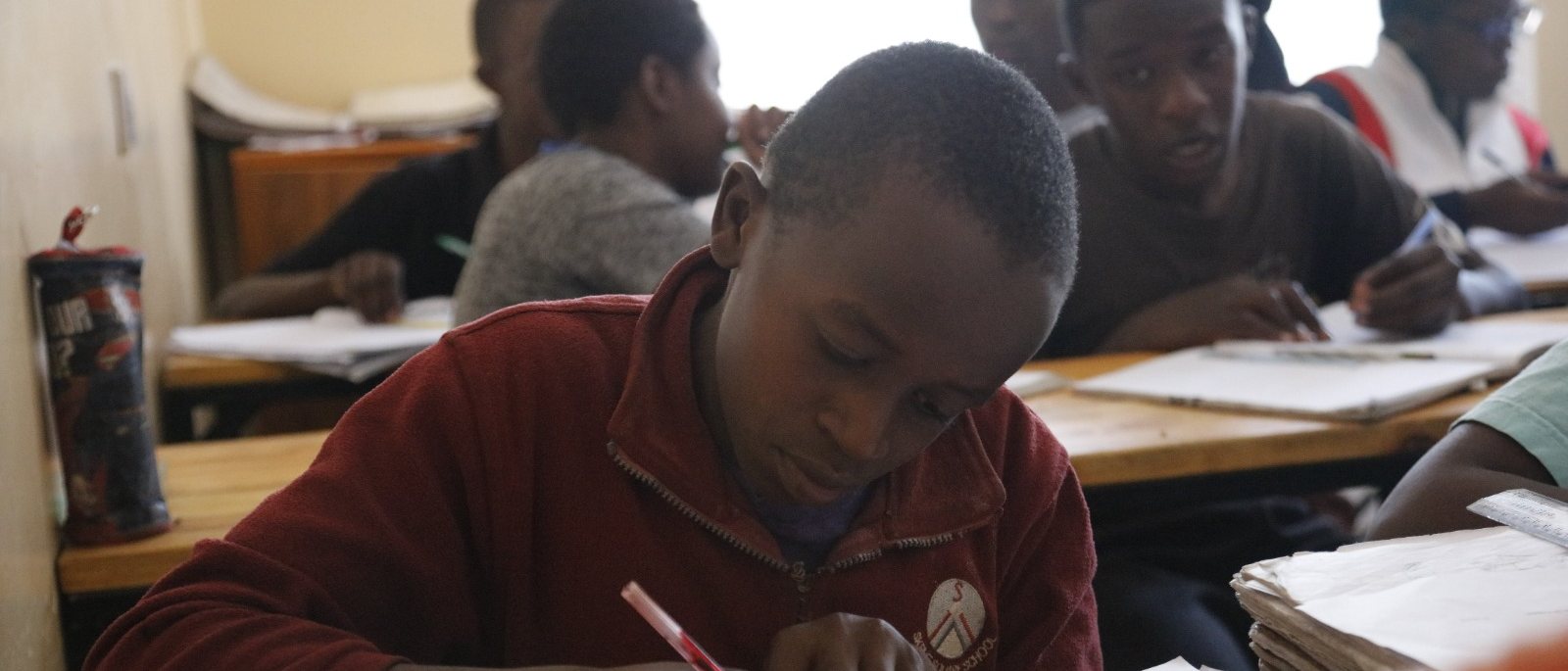 Students bent over their notebooks at Wezesha study tables